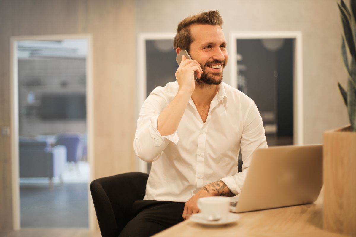 Commercial souriant au téléphone devant son ordinateur