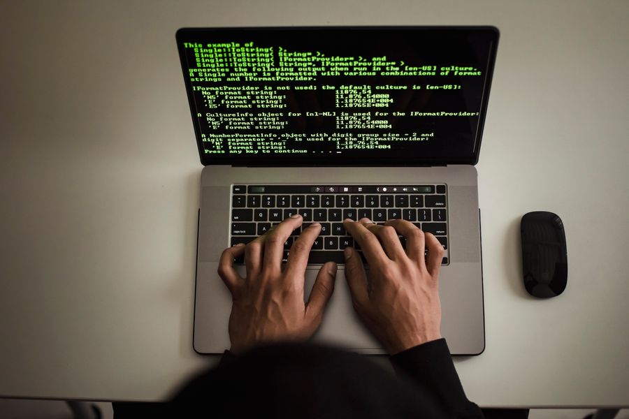 Mains tapant sur un clavier avec du code affiché à l'écran